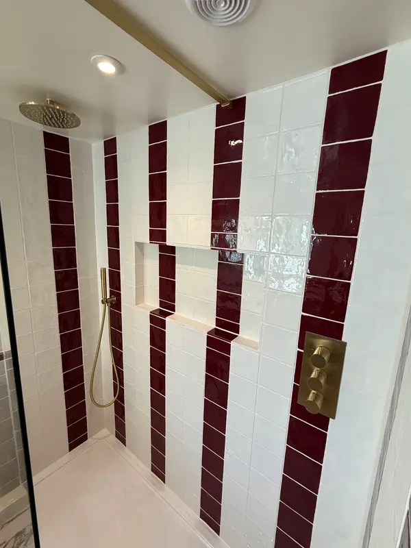 Shower with burgundy and white tiles and brushed brass fittings